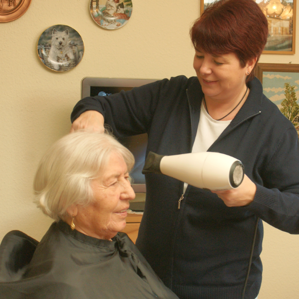 Friseurin frisiert einer alten Dame die Haare